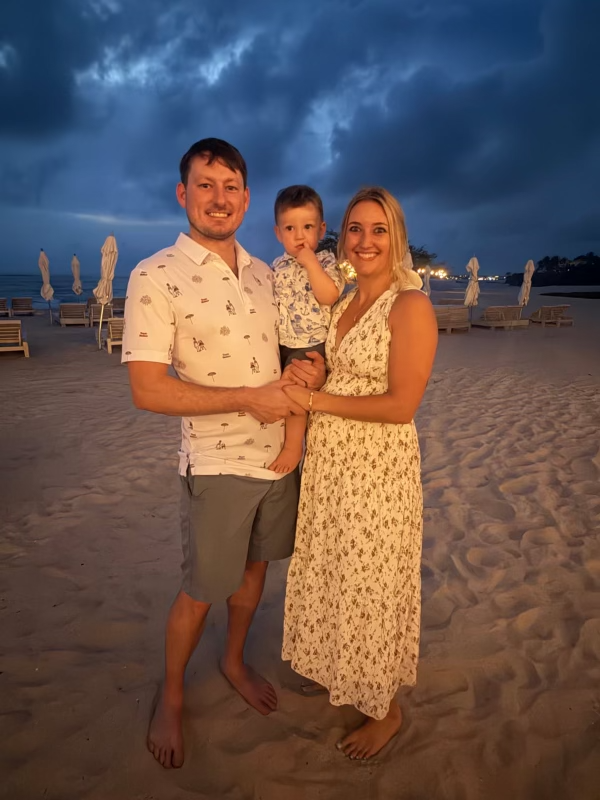 Ryan Schmid with his wife and son on the beach at dusk